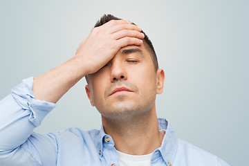 Image showing unhappy man with closed eyes touching his forehead