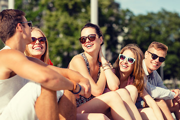 Image showing group of smiling friends sitting on city street