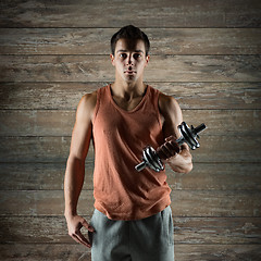 Image showing young man with dumbbell flexing biceps