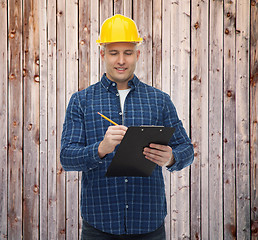 Image showing smiling male builder in helmet with clipboard