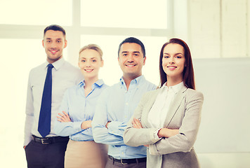 Image showing smiling businesswoman in office with team on back