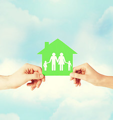 Image showing hands holding green house with family