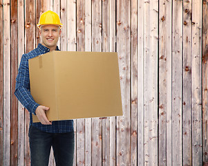 Image showing smiling male builder in helmet with cardboard box