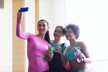 Image showing happy women with smartphone taking selfie in gym