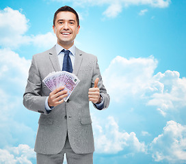 Image showing smiling businessman with money showing thumbs up