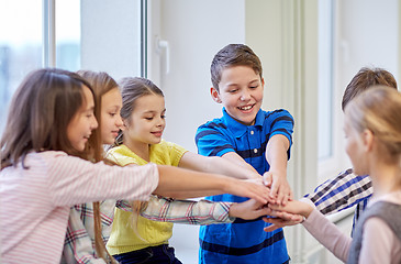 Image showing group of smiling school kids putting hands on top