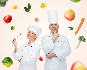 Image showing happy chef couple or cooks over food background