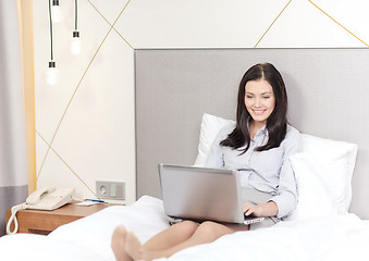 Image showing happy businesswoman with laptop in hotel room