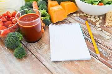 Image showing close up of ripe vegetables and notebook on table