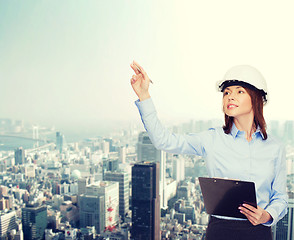 Image showing smiling businesswoman in helmet with clipboard