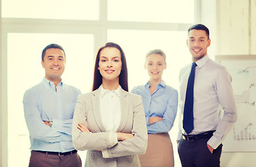 Image showing smiling businesswoman in office with team on back