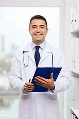 Image showing happy doctor with clipboard in medical office