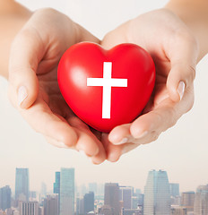 Image showing close up of hands holding heart with cross symbol