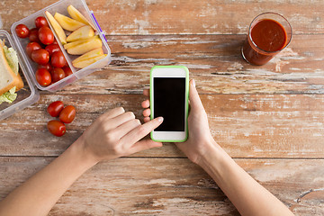 Image showing close up of hands with smartphone food on table