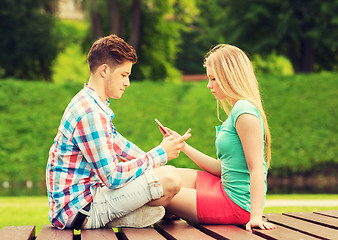 Image showing couple with smartphones sitting on bench in park
