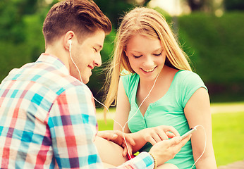 Image showing smiling couple with smartphone and earphones