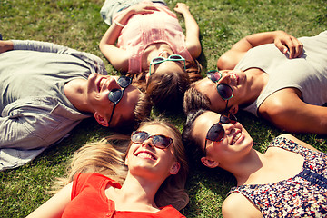 Image showing group of smiling friends lying on grass outdoors