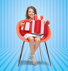 Image showing happy little girl with gift boxes sitting on chair