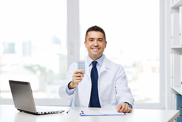 Image showing smiling doctor with tablets and laptop in office