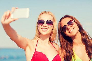 Image showing two smiling women making selfie on beach