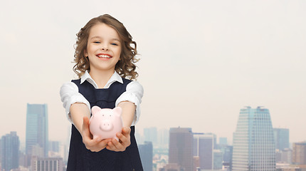 Image showing happy girl holding piggy bank on palms