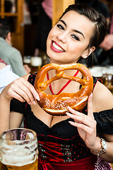 Image showing Woman in Dirndl eating Oktoberfest Pretzel