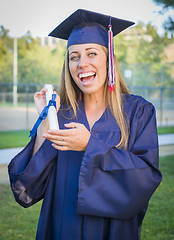 Image showing Expressive Young Woman Holding Diploma in Cap and Gown