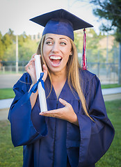 Image showing Expressive Young Woman Holding Diploma in Cap and Gown