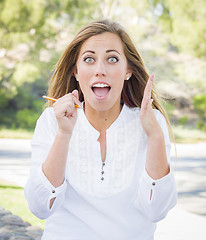 Image showing Excited Young Woman With Pencil Outdoors