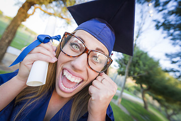 Image showing Expressive Young Woman Holding Diploma in Cap and Gown