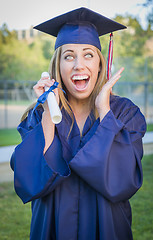 Image showing Expressive Young Woman Holding Diploma in Cap and Gown
