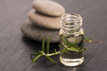 Image showing Essential oil with rosemary and fresh green leaves 