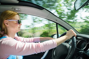 Image showing Smiling beautiful woman in sunglass driving car at high speed