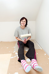 Image showing housewife resting after painting wall to white
