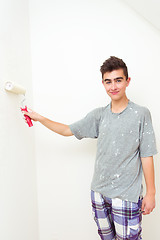 Image showing teenager painting wall to white at home