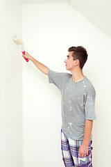 Image showing teenager painting wall to white at home