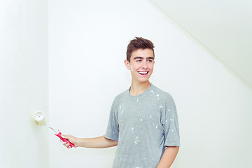 Image showing teenager painting wall to white at home