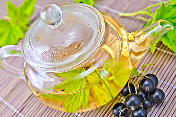 Image showing Tea with black currants in glass teapot on bamboo napkin