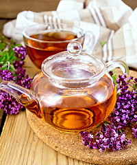 Image showing Tea from oregano in glass teapot and cup on board