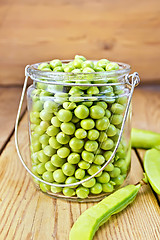 Image showing Green peas in glass jar on wooden board