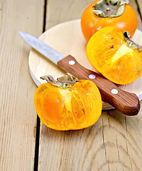 Image showing Persimmon with knife on wooden board