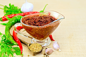 Image showing Adjika in glass gravy boat with garlic on sacking