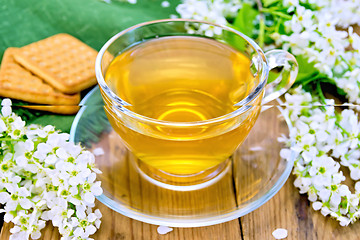 Image showing Tea in cup with cookies and flowers of bird cherry on board