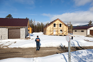 Image showing Worker in overalls making notes on construction site