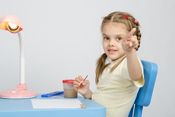 Image showing Girl painting paints at table, points the finger