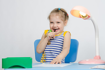 Image showing Girl laughing stuck a pencil in her mouth