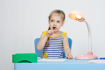 Image showing Girl thinking stuck a pencil in her mouth