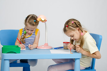 Image showing Two girls drawing at table draw paints and pencils