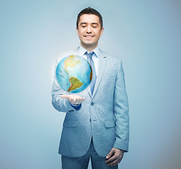 Image showing happy businessman in suit showing globe hologram