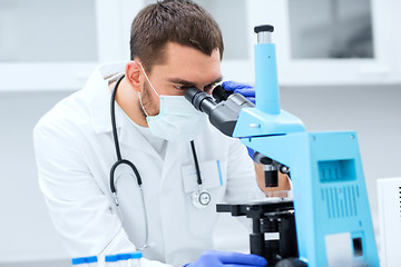 Image showing young scientist looking to microscope in lab